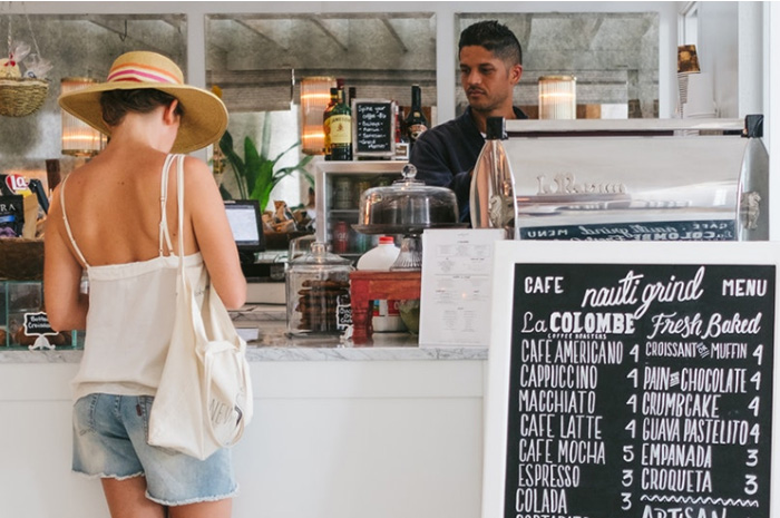 Lady paying for meal at cafe wearing summer clothes and hat