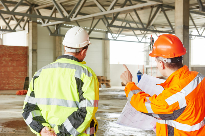 Two tradesmen on construction site in protective clothing