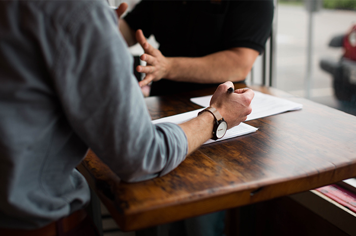 Two men sitting at a table discussing business with papers