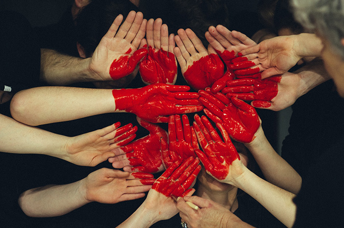 Hands placed in middle of a circle with red paint forming shape of a heart