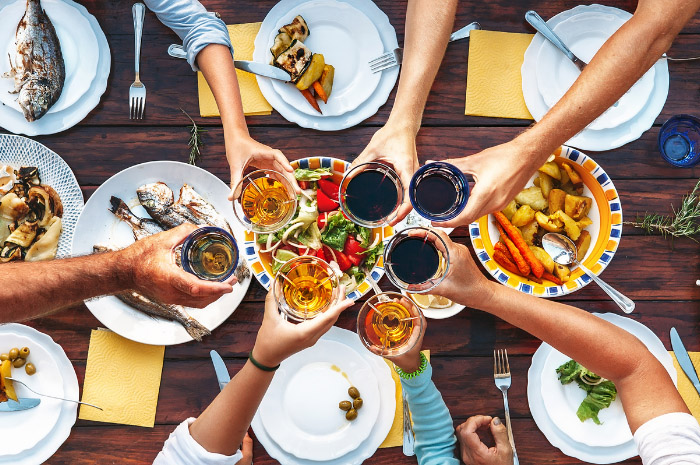 Family members sitting at dinner table cheering glasses