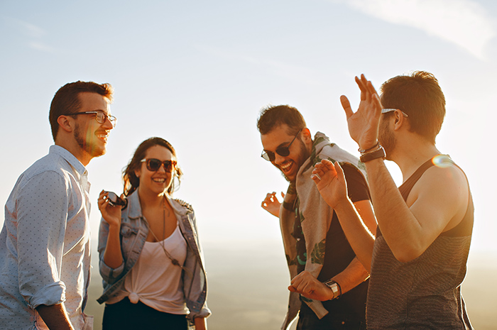 4 young adults dancing and chatting in a circle