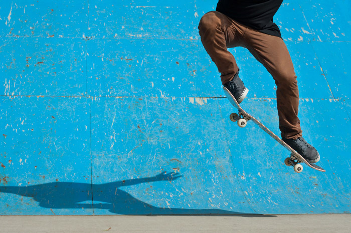 Man skateboarding in air with blue background wall