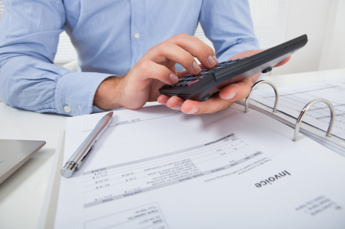 Man in blue business shirt using calculator of folder of taxation receipts and invoices