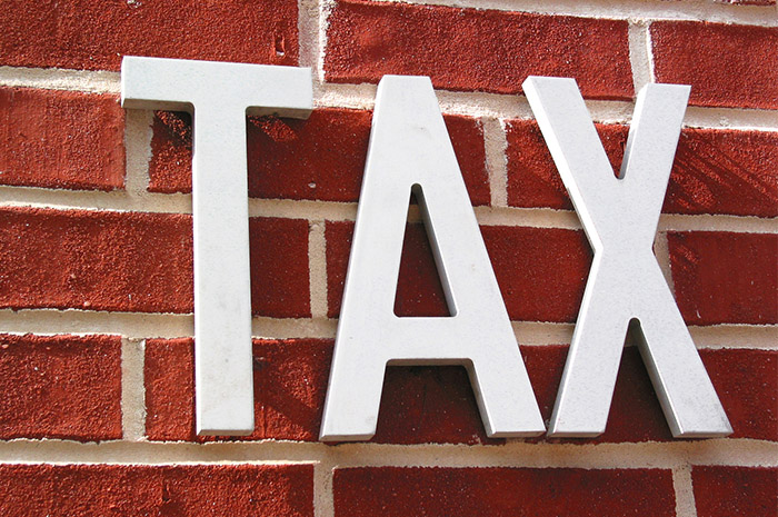 White letters TAX on red brick wall