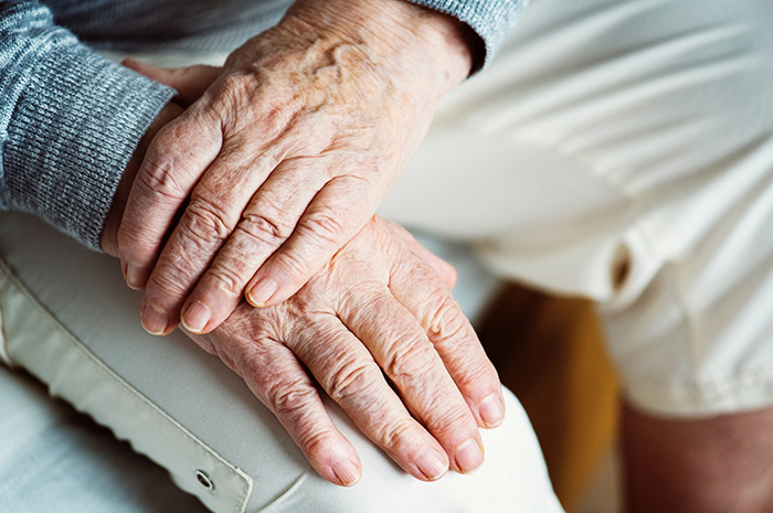 Elderly man sitting with aged hands on knee