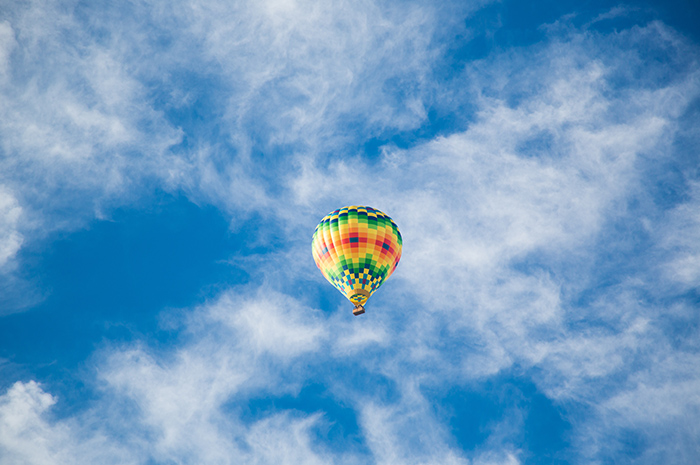 Hot air balloon up in the blue sky with white clouds