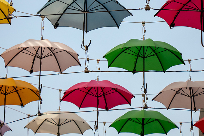 Numerous coloured umbrellas hung up on railings
