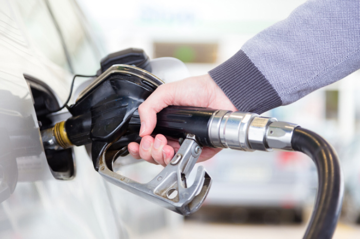 Person holding fuel pump filling up motor vehicle with petrol