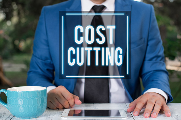 Man in blue business suit with tablet and coffee cup and wording COST CUTTING