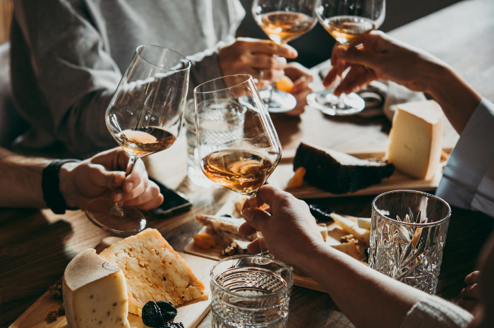 Team cheering wine glasses over array of cheeses and dips as workplace entertainment