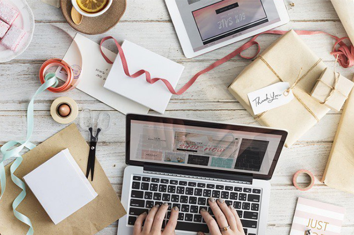 Desk covered in wrapping paper and string with laptop typing on keyboard