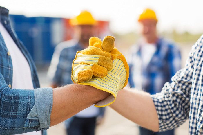 Tradesman and business man handshake on construction site