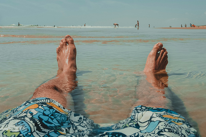 Man relaxing on beach wearing blue printed boardshorts