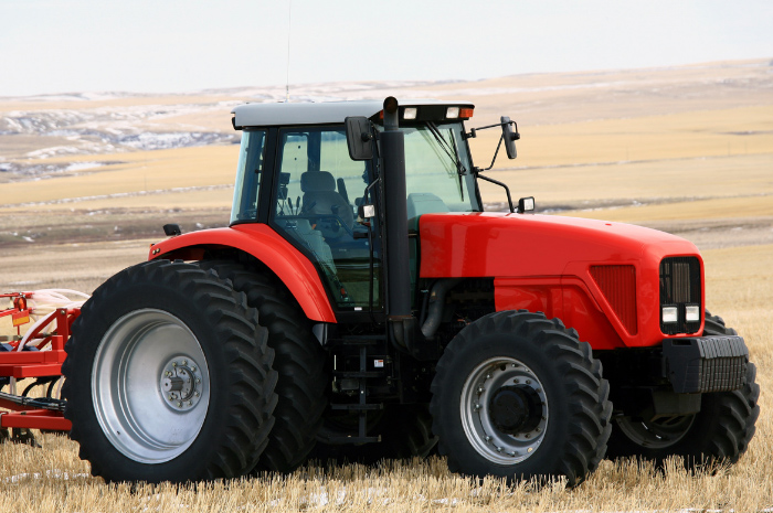 Red tractor with implements parked in wheat fields