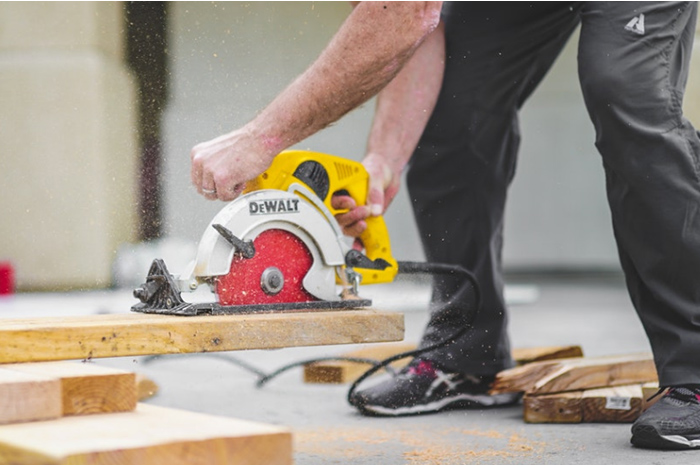 Tradesman sawing wood with electric power tool