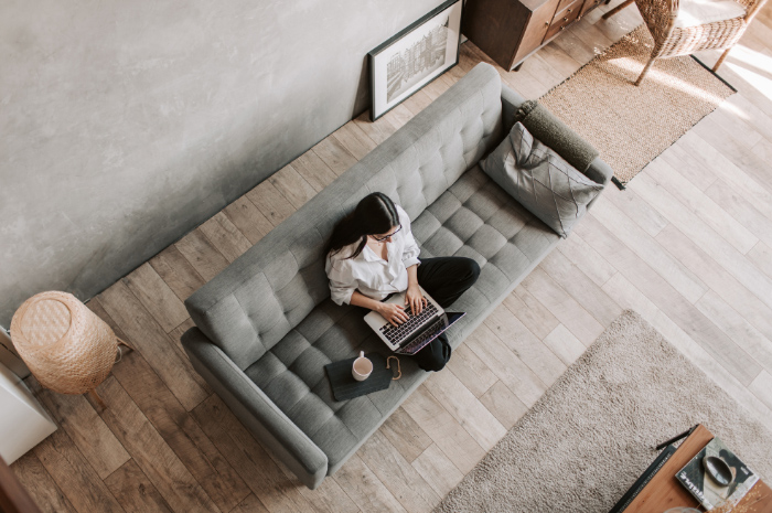 Female employee sitting on couch with laptop working from home