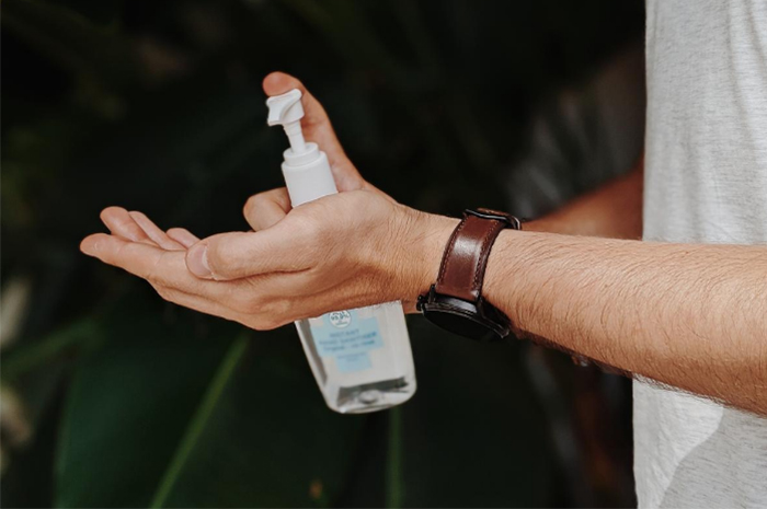 Hands out holding sanitizer pumping product in palm