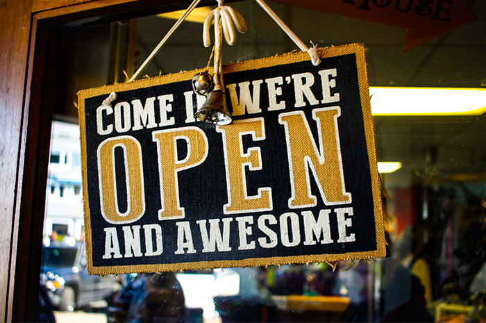 Open sign on shop door saying come in we are open and awesome