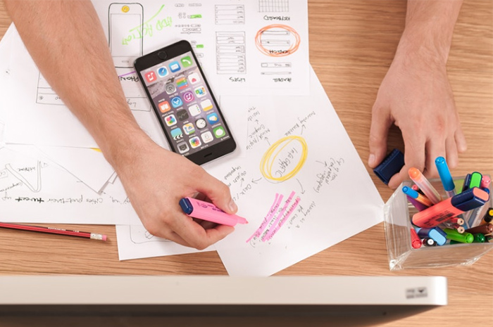 Mans arms highlighting words on paper sitting at desk with colourful pens in pen holder