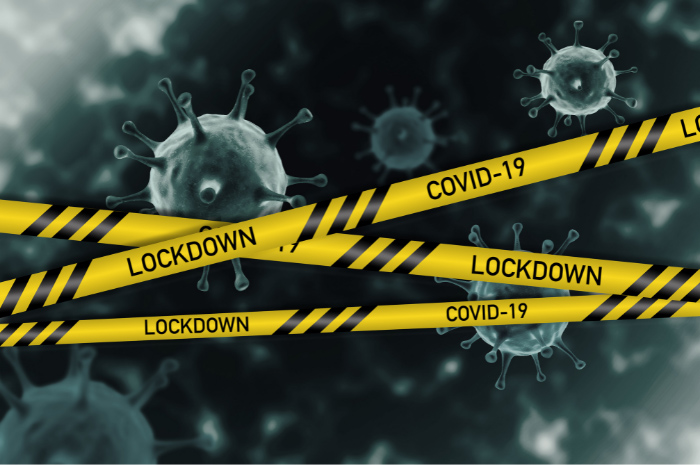 Coronavirus symbols floating around with yellow safety warning tape reading COVID-19 LOCKDOWN