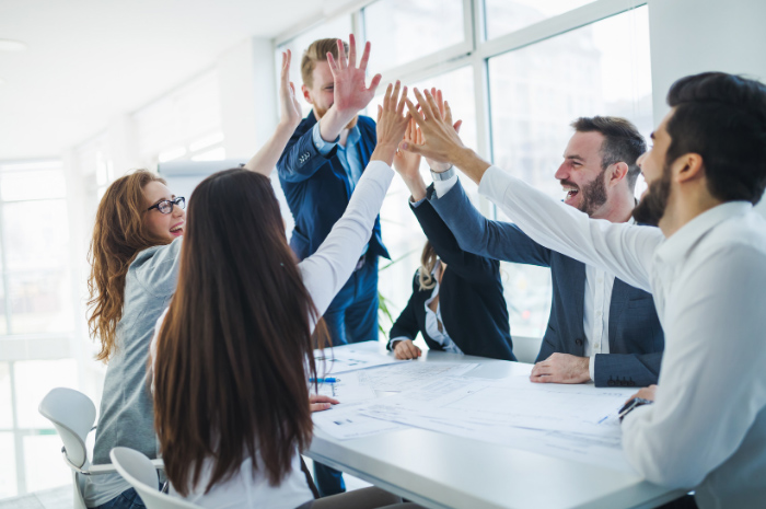 Team in corporate workplace high fiving