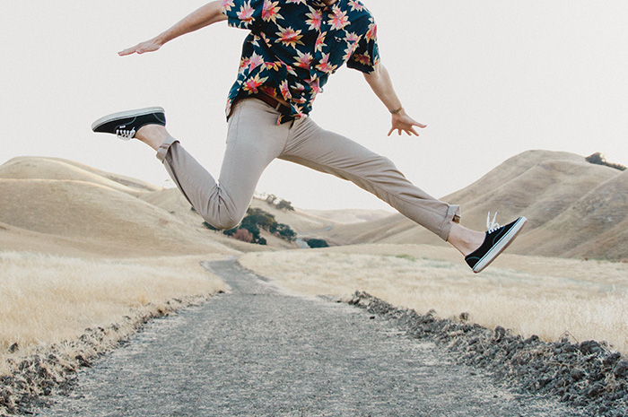 Man jumping in the air leaping over road with arms out wide