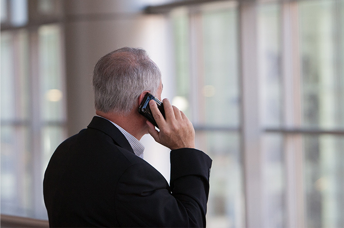 Older gentleman facing towards window speaking on mobile phone