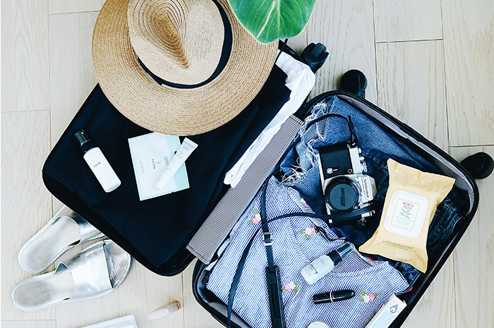 Suitcase open with camera clothing hat and shoes