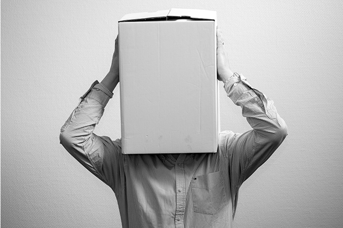 Man in corporate business shirt holding cardboard box over his head