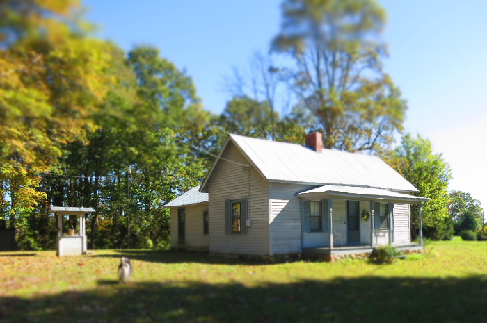 Small old house granny flat sitting in green grass field