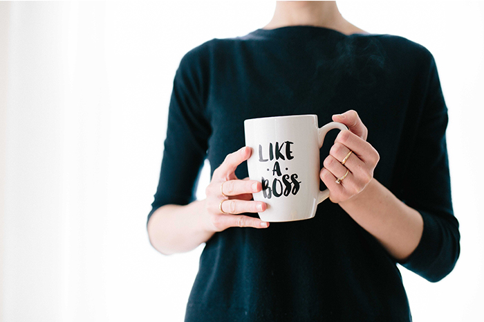 Business woman in black shirt holding coffee cup with wording LIKE A BOSS