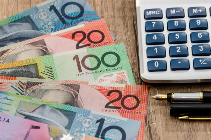 Australian currency notes on desk beside calculator and pens