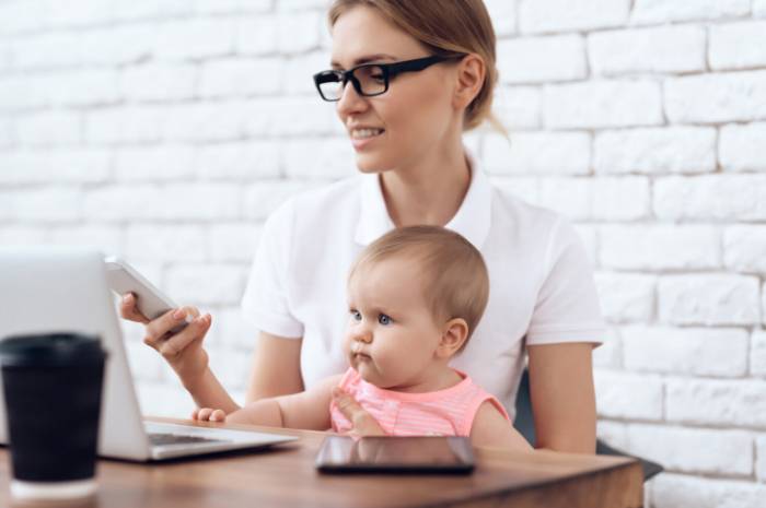 Working mother at desk on phone with baby on her lap