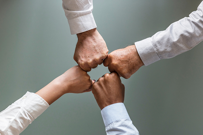 Four staff members fist pumping with white business shirts