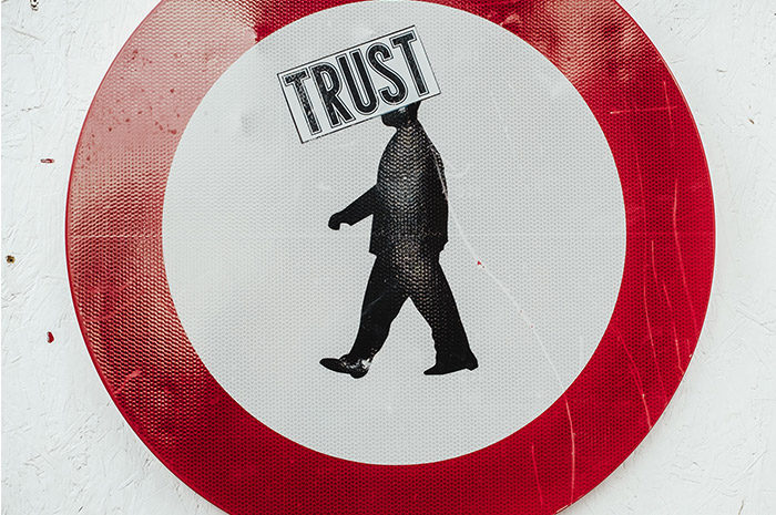 Red circle with silhouette of man in centre and words TRUST