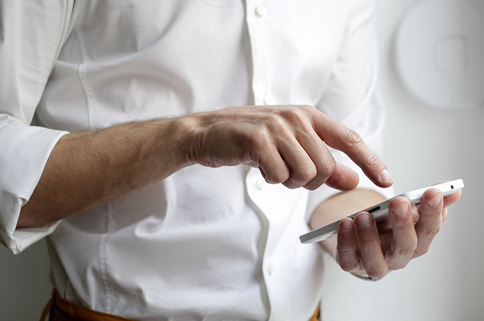 Man wearing white business shirt typing message on phone