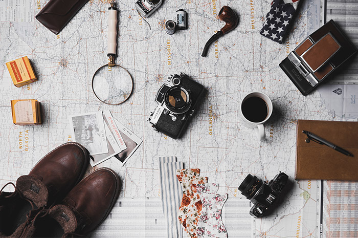 Travelling items spread over map boots camera magnifying glass photos cup of coffee
