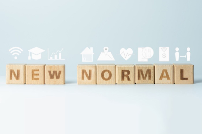 Wooden letter blocks spelling NEW NORMAL with pandemic related icons above in white