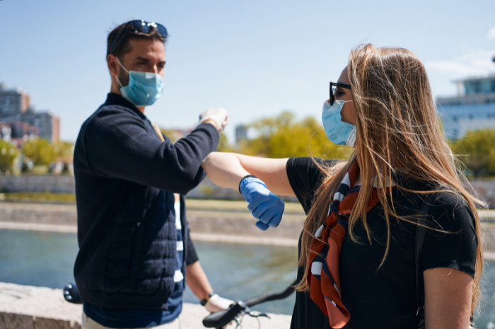 Man and women touching elbows wearing masks on the street