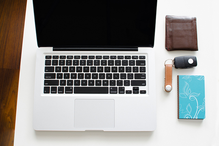 Laptop on desk near wallet keys and notebook