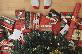 Presents under Christmas tree and little feet standing nearby wearing socks