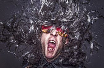Man with crazy black wig and red and yellow glasses calling out