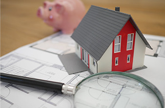 House plans with house piggy bank and magnifying glass