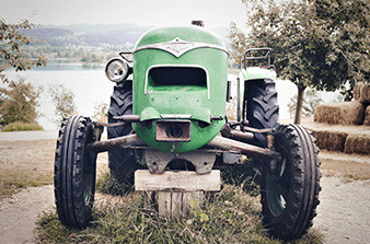 Green tractor in fields hay bales in background