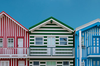 Three houses in a row red green and blue and white striped paint