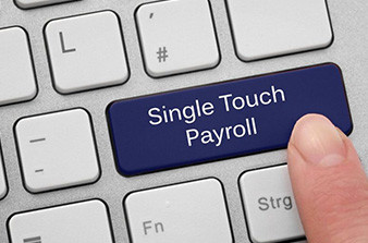 Finger pressing key with wording Single Touch Payroll on computer keyboard