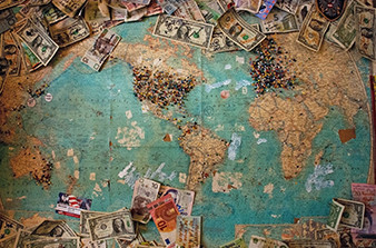 World map with pins over cities and countries numerous currency notes on top and bottom