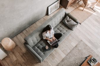 Female employee sitting on couch with laptop working from home